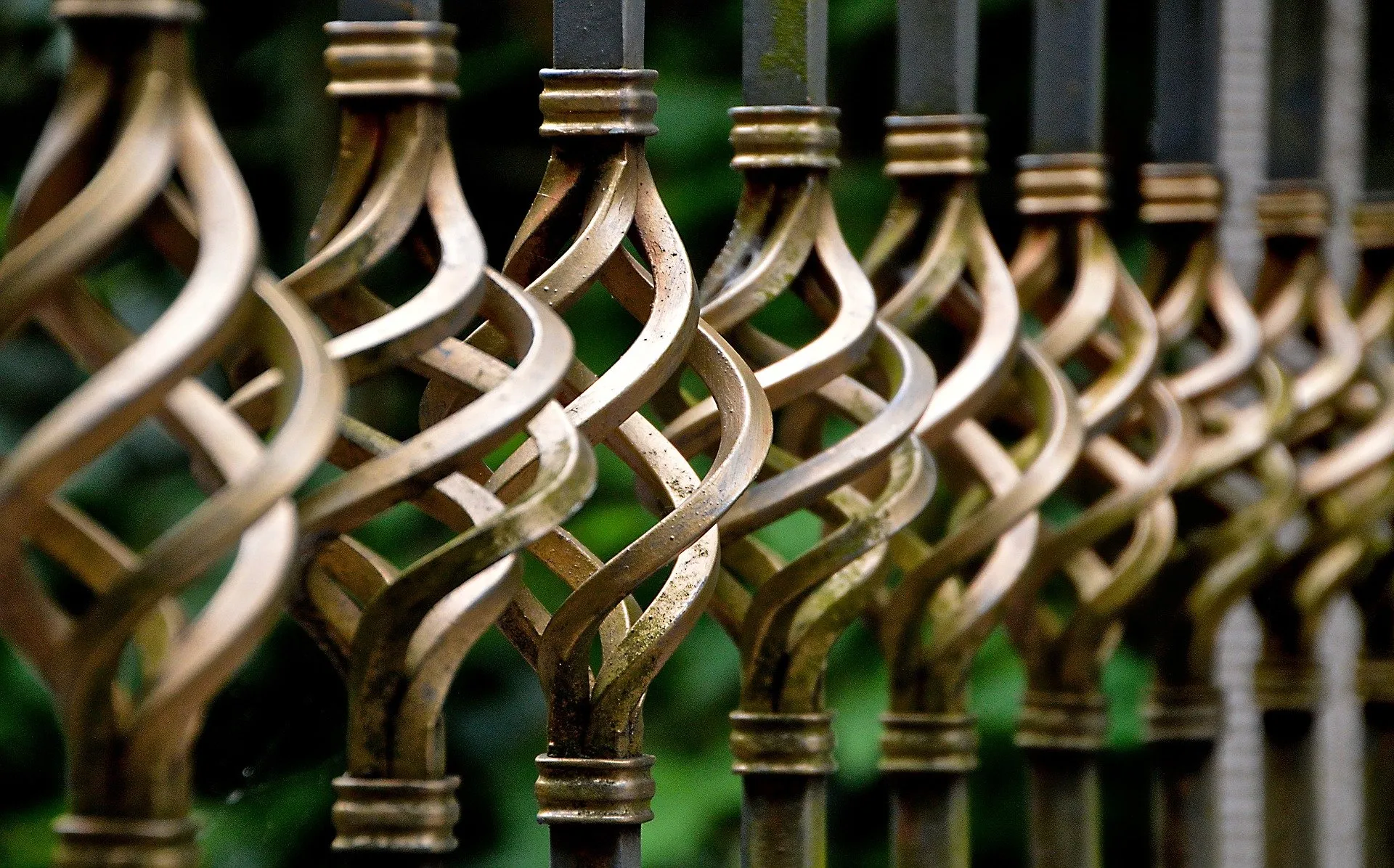 Decorative wrought iron fence exhibiting the fibrous grain structure of wrought iron components